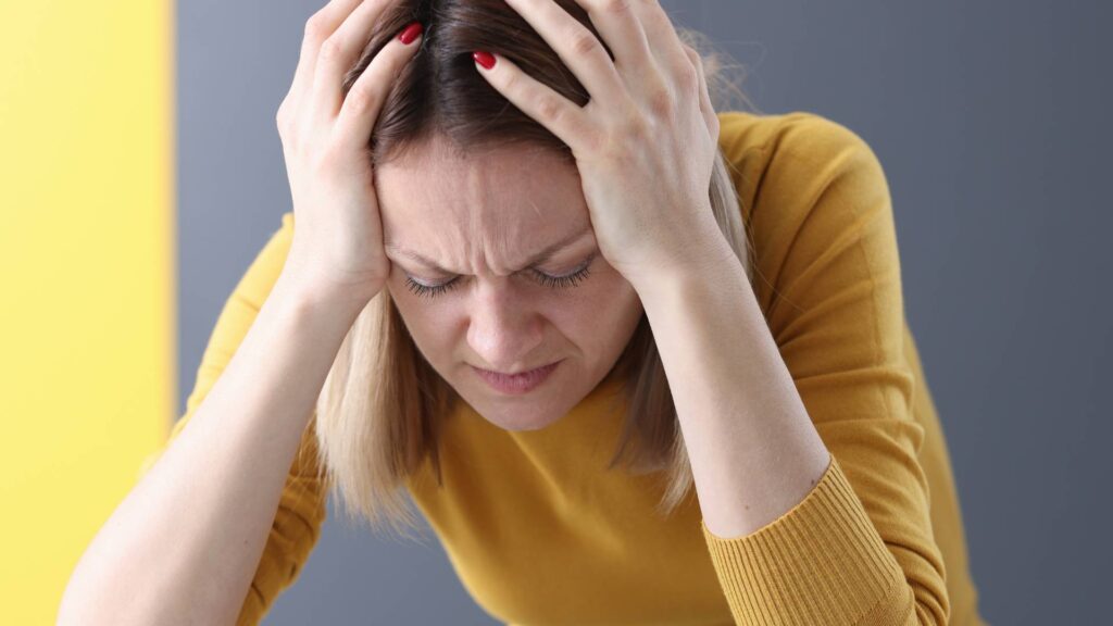 woman with her hands on her head showing signs of pain due to a headeache of not knowing how many mice do i have in my house