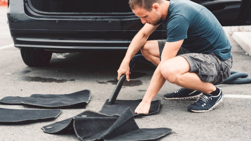 man cleaning rat urine from the carpets of his car following the guide on How to Get Rid of Rat Urine Smell in Your Car