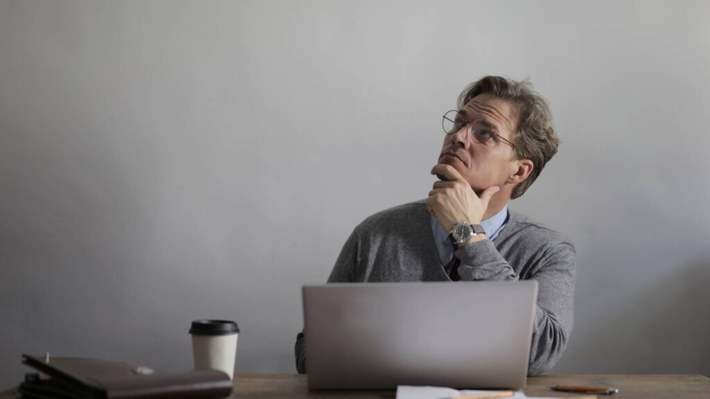 Thoughtful male manager working on laptop in modern workspace thinking about removing wasp nests naturally