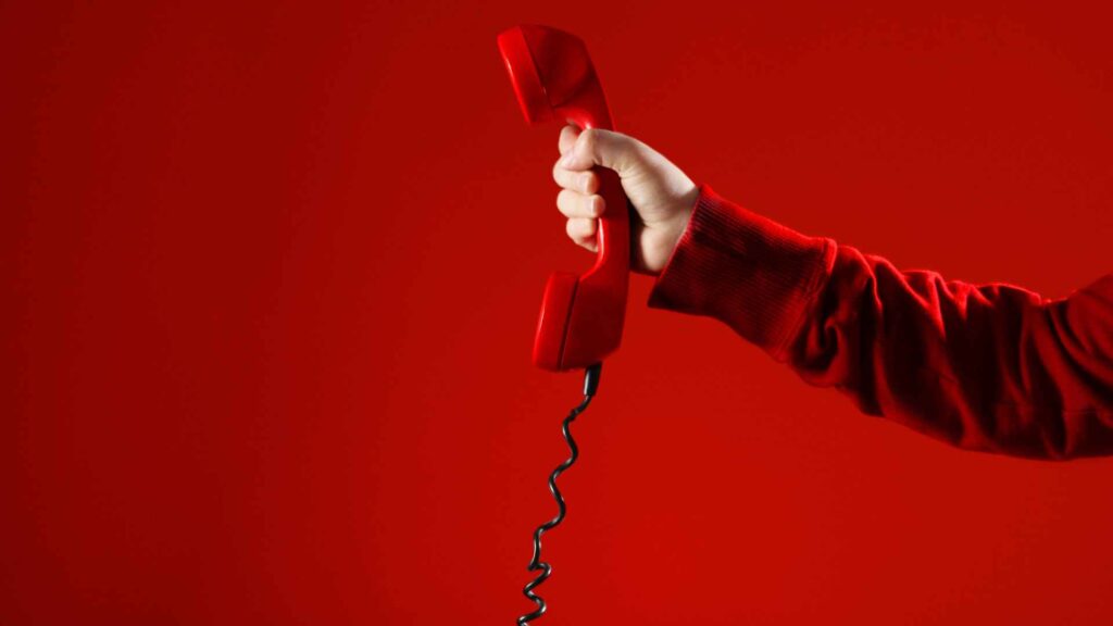 red phone on hand with a red sweater and red background to illustrate when to call professionals for quick flea treatment for house