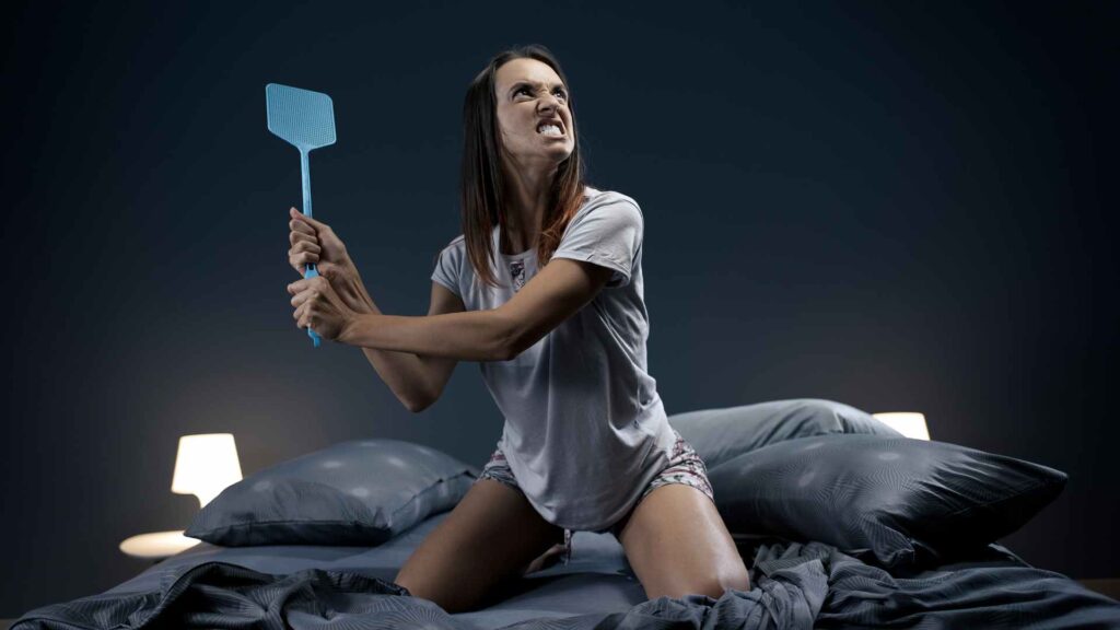 a woman holding a fly swatter as the best mosquito killer for bedroom