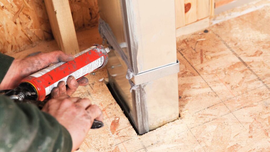 worker using caulking on a construction to represent one of the ways you can seal mice entry points